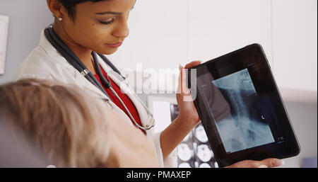 Afrikanische amerikanische Arzt überprüfen x-ray mit erwachsenen Patienten Stockfoto