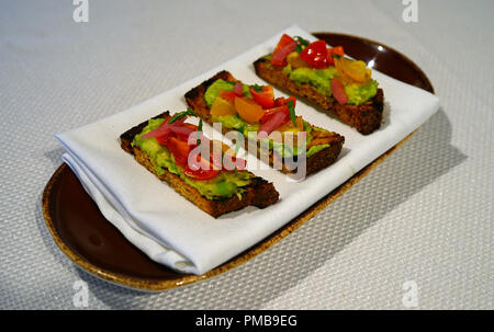 Scheiben von Sauerteig vegan avocado Toast mit Tomaten auf der Oberseite Stockfoto