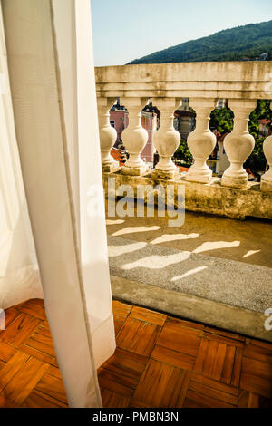 Fließende Gardinen wehen im Wind, als sie zu der alten Europäischen hotel Balkon mit Blick schaffen eine romantische Atmosphäre in Opatija, Kroatien führen. Stockfoto