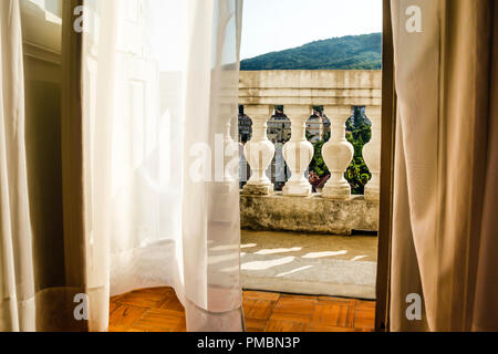 Fließende Gardinen wehen im Wind, als sie zu der alten Europäischen hotel Balkon mit Blick schaffen eine romantische Atmosphäre in Opatija, Kroatien führen. Stockfoto