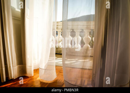 Fließende Gardinen wehen im Wind, als sie zu der alten Europäischen hotel Balkon mit Blick schaffen eine romantische Atmosphäre in Opatija, Kroatien führen. Stockfoto