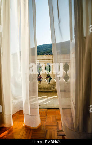 Fließende Gardinen wehen im Wind, als sie zu der alten Europäischen hotel Balkon mit Blick schaffen eine romantische Atmosphäre in Opatija, Kroatien führen. Stockfoto