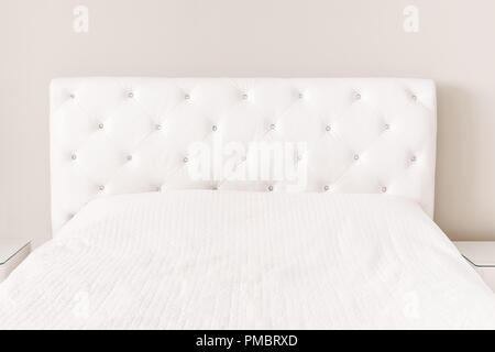 Leeres weißes Bett mit Daunendecke Bettdecke. Hauptschlafzimmer mit hellen Wänden. Moderne Möbel zu Hause mit niemand. Hintergrund mockup mit Copyspace fo Stockfoto