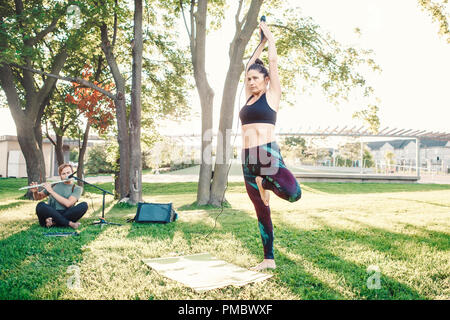 Weiße Kaukasier mittleren Alter Frau Yoga im Park draußen auf den Sonnenuntergang. Weibliche Person Stretching, Durchführung von Training im Freien. Gesunder Lebensstil moderner Stockfoto