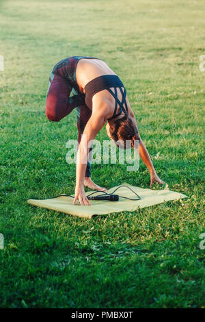 Weiße Kaukasier mittleren Alter Frau Yoga im Park draußen auf den Sonnenuntergang. Weibliche Person Stretching, Durchführung von Training im Freien. Gesunder Lebensstil moderner Stockfoto