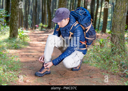 Portrait von asiatischen reisenden Mann Schnürsenkel binden, bevor der Wald erkunden Stockfoto