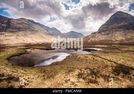 Eine kleine lochan See steht auf moorigen Heidelandschaft auf dem Gipfel der Pass zwischen Glen Coe und Glen Etive auf Rannoch Moor, unter den Bergen von Buachai Stockfoto