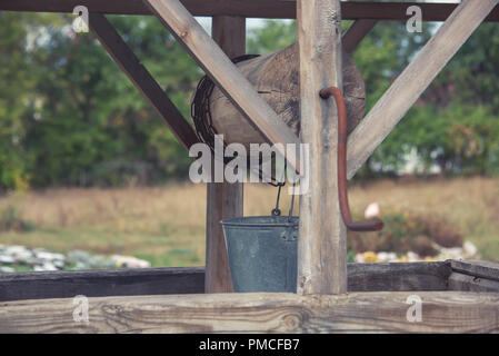 Die alten Brunnen für Wasser mit einem Deck, eine Schaufel und eine Kette, Stockfoto