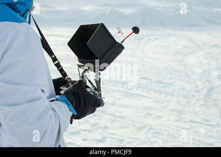 Der Mensch ist eine professionelle Fernbedienung von einem quadrocopter vor dem Hintergrund der Schnee Stockfoto