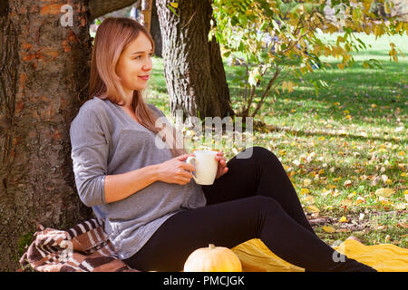 Schwangere Frau in einem Herbst Park ruhenden Stockfoto