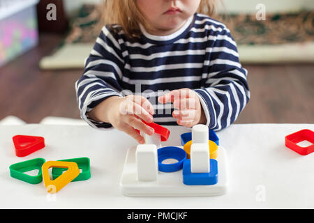 Kind 1,5 Jahre am Tisch sitzen und spielen mit einem sich entwickelnden Spielzeug, Montessori Technik, die Hände des Kindes besetzt Spielen Stockfoto