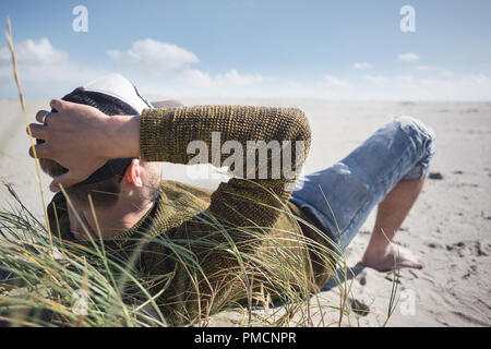 Mann, der an einem Strand an der Nordsee liegen Stockfoto