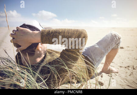 Mann, der an einem Strand an der Nordsee liegen Stockfoto