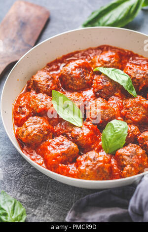 Leckeres Rindfleisch Frikadellen in Tomatensoße mit Gewürzen und frischem Basilikum auf einem Küchentisch. Essen Fotografie, vertikaler, europäische Küche. Stockfoto