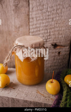 Hausgemachte Apple Jam in Bank im Herbst Hintergrund mit reife Äpfel und grüne Blätter auf dem alten Holztisch, vertikale Foto Stockfoto