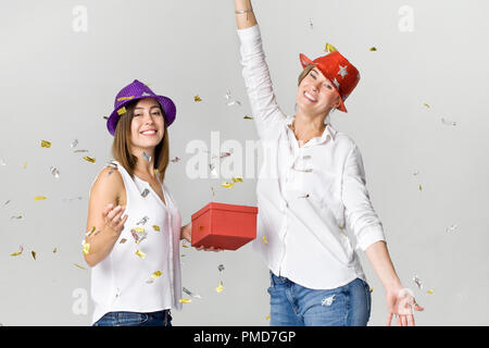 Partei Freundinnen mit Konfetti, Geschenk und bunte Hüte. Es ist Entspannung und Tanz Zeit Stockfoto