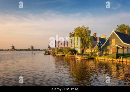 Sonnenuntergang über historische Bauernhäuser und Windmühlen im schönen Holland Village der "Zaanse Schans" in der Nähe von Amsterdam in den Niederlanden. Stockfoto