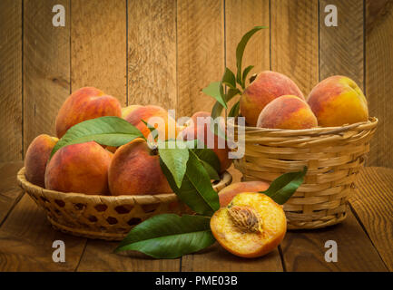 Reif und schöne Pfirsiche in einem Korb auf einem hölzernen Hintergrund. Stockfoto