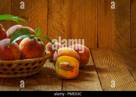 Reif und schöne Pfirsiche in einem Korb auf einem hölzernen Hintergrund. Stockfoto
