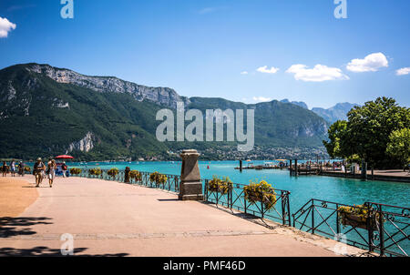 See von Annecy Bank und Bürgersteig mit Französischen Alpen Berge im Hintergrund Stockfoto