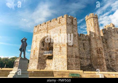 Caernarfon Castle im Norden von Wales mit Bronze Statue des David Lloyd George Premierminister des Vereinigten Königreichs, 1916-22. Stockfoto