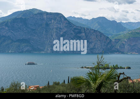 Aussicht über den Gardasee mit einem Boot überqueren und die Berge und einem bewölkten Himmel im Hintergrund, Bild vom oberen Teil des Dorfes Assenza di Brenzone auf Stockfoto