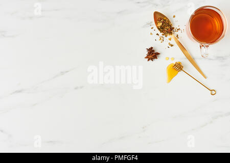 Tee- Konzept. Blick von oben auf die frischen schwarzen Tee, mit goldenen Löffel, Pendelarm mit Honig und Kräutern auf weißem Hintergrund. Flach mit kopieren. Stockfoto