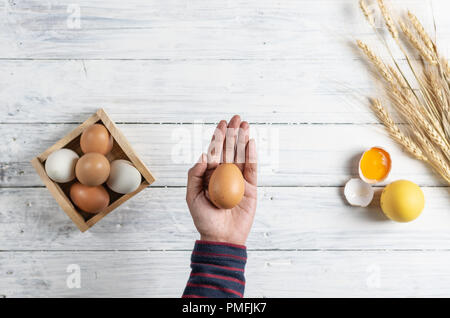 Hand braun Ei auf weißem Holz Hintergrund Stockfoto