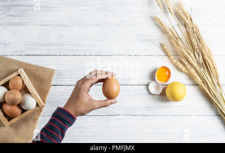 Hand braun Ei auf weißem Holz Hintergrund Stockfoto