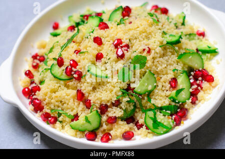 Couscous Salat mit Granatapfel, Minze und Gurken, gesunde Hausmannskost, vegane Mahlzeit Stockfoto