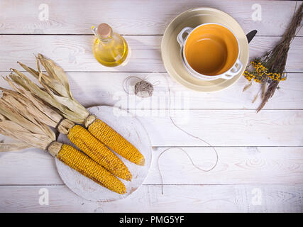 Gebackene gegrillte Maiskolben auf weißem Holz- Hintergrund. Ansicht von oben. Stockfoto