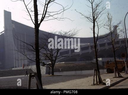 Seitenansicht mit architektonischen Details und öffentlichen Platz mit Bäumen im Yoyogi National Stadium, Tokio, Japan, 1963. () Stockfoto