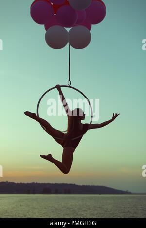 Mädchen Acrobat schwebt in der Luft auf den Ballons, hält es für die akrobatische Ring. Stockfoto