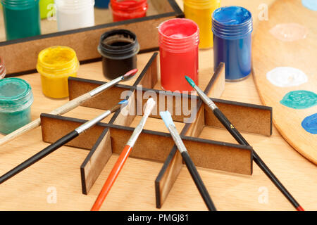 Holzboden und Box mit Farben und Pinsel auf hölzernen Schreibtisch Stockfoto