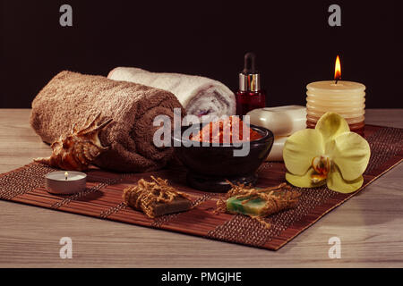 Spa und Wellness Ambiente mit Orchidee, Schüssel mit Meersalz, Seashell, Flasche mit aromatischen Ölen, Seifen, Kerzen und Handtuch auf Bambus Serviette Stockfoto