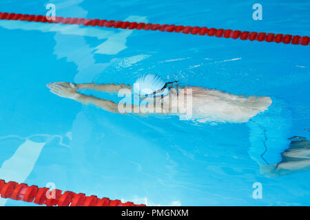 Foto von athletischen Mann in blaue Kappe floating auf dem Weg in Pool Stockfoto