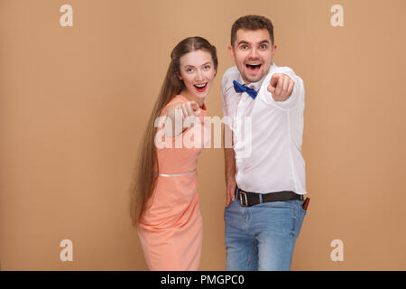 Wow, wir finden Sie! Portrait von gutaussehenden Mann im weißen Hemd und der Frau im rosa Kleid zeigen und auf Kamera mit überrascht, erstaunt, Gesicht Stockfoto