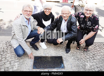 18. September 2018, Berlin: Der Zeitzeuge Manfred Höer (L-R), seine Frau Inga, sein Bruder Peter und Christa Schöpf knien vor einer Gedenktafel bei der Einweihung zum Gedenken an den Tunnel die Flucht der beiden Brüder am Checkpoint Charlie in der Zimmerstraße in 1972. Foto: Jörg Carstensen/dpa Stockfoto