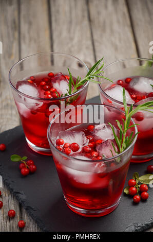 Erfrischendes Getränk mit Preiselbeeren und Rosmarin auf Holz- Hintergrund. Stockfoto