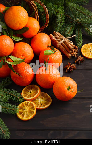 Frische Mandarinen Clementinen mit Gewürzen auf dunklem Hintergrund, Weihnachten Konzept Stockfoto