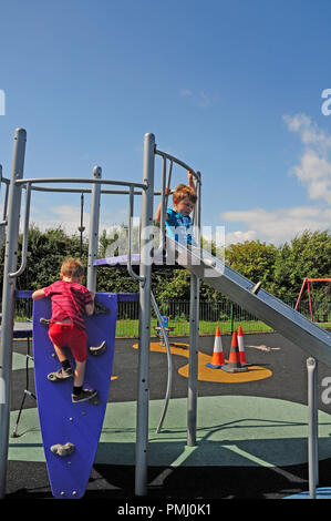 Vier Jahre alten Jungen und sieben Jahre alten Jungen spielen auf einer Folie in einer Play Park. Stockfoto