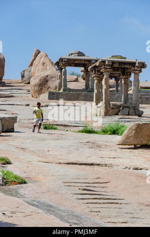 Einsamer Mann neben riesige Felsbrocken und Stein Strukturen auf der Hemakuta Hügel bei Hampi, Karnataka, Indien Stockfoto