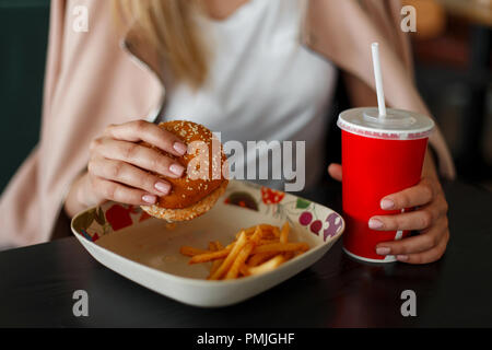 Mädchen, dass eine Hamburger, Fast Food zu essen und trinken Cola Stockfoto