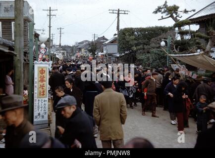 Eine große Masse von Menschen sammeln und Shop auf einer belebten Einkaufsstraße in Japan, mit Restaurant im Vordergrund mit dem Schild oba Shumai Reis Curry fühlen Sie bitte sich frei, mit uns in japanischer Schrift, 1965 zu besuchen. () Stockfoto