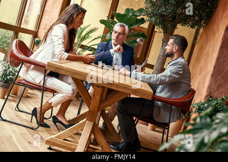 Business Lunch. Drei Leute im Restaurant am Tisch Denken von kreativen Ideen ernst zu sitzen. Team Konzept Stockfoto