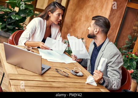 Business Lunch. Die Leute am Tisch im Restaurant diskutieren Projekt lebendige Menschen quetschen Papier wütend Sitzen Stockfoto