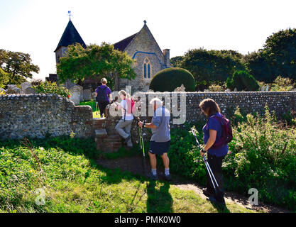 Wanderer auf öffentlichen Fußweg auf Snow Hill Überquerung der Stile im Feuerstein Wand über St. Peter und Paul Kirche West Wittering, West Sussex, Großbritannien Stockfoto