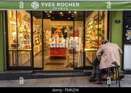 ISTANBUL, Türkei - 29 Dezember, 2015: Shoeshiner polieren Schuhe vor der lokalen Yves Rocher mit den Zeichen. Yves Rocher ist eine französische Cosmet Stockfoto