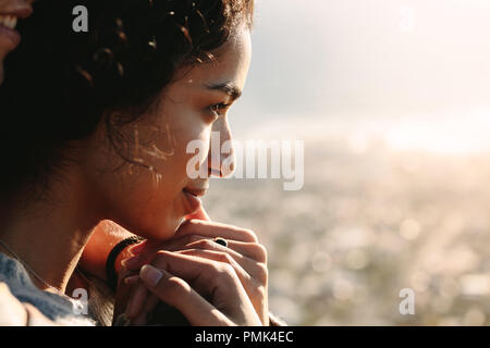 Nahaufnahme der jungen Frau Gesicht schaut auf einen Blick im Freien. Frau von ihrem Mann umfaßt wird von hinten. Stockfoto