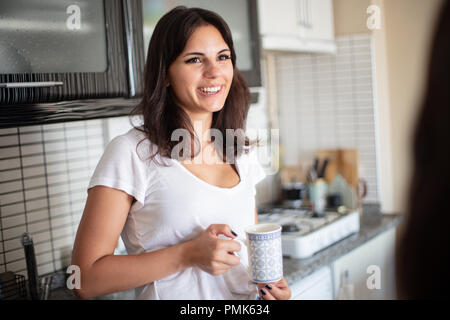 Hübsche, junge Frau im Chat mit einem Freund zuhause zu Hause in einer über die Schulter Blick auf sie lächelnd Happy Face Stockfoto